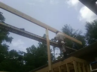 Carpenter setting a ridge beam over a new addition frame — Ice Dam Removal by Roofing Brothers in Lacota
