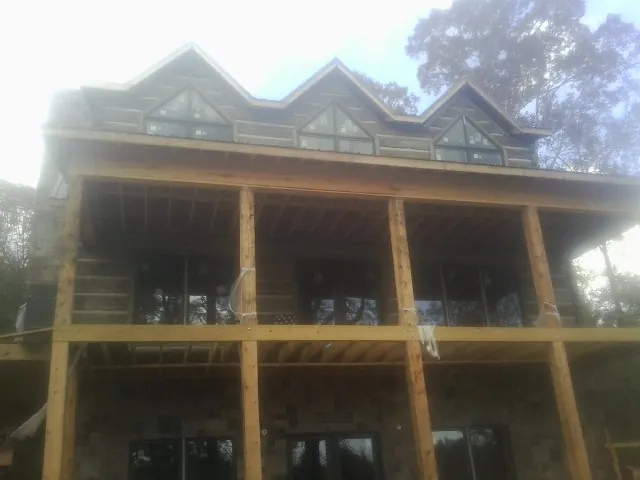 Dormers and porch framing on a large log home under construction — Roof Coating work by our crew in Lacota