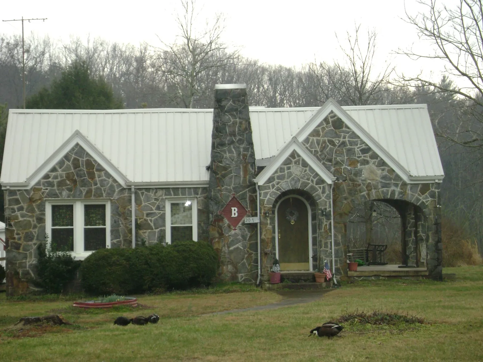 White metal roof on a stone cottage with steep gables in Lacota