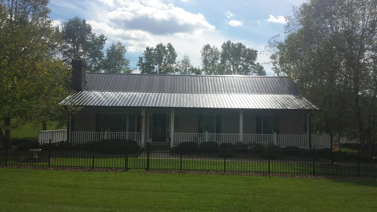 Gray metal roof on a brick ranch with a full width front porch — Gutter Guard Installation work by our crew in Lacota