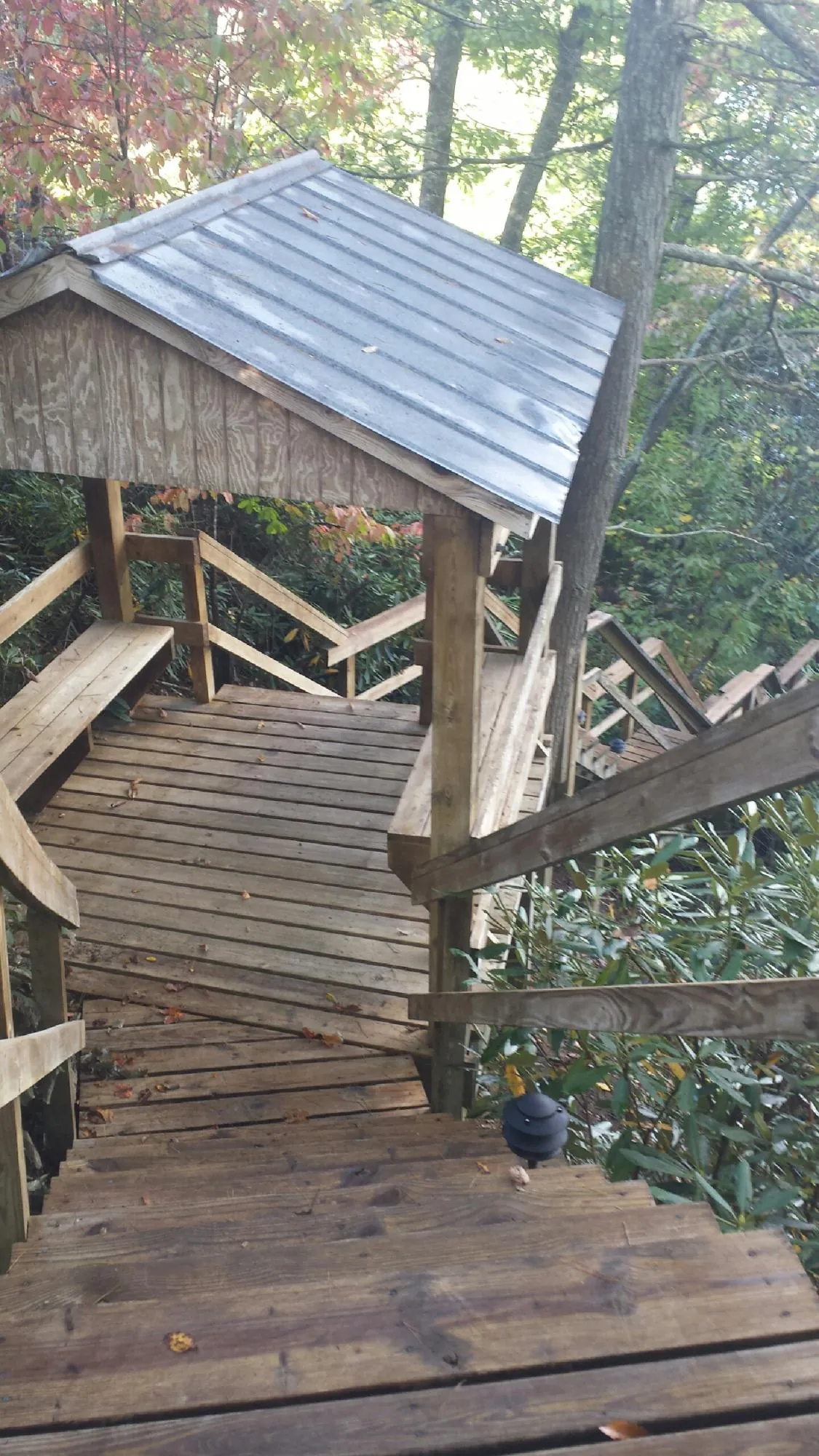 Metal roofed shelter over wooden steps on a wooded walkway — Skylight Repair & Installation work by our crew in Lacota